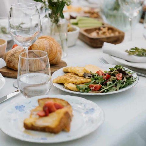Brunch plates on set table - croissants, omelette with garden salad, and French toast on plates