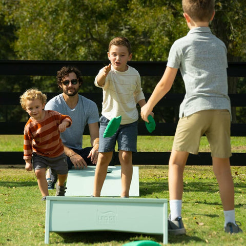 A family of boys playing cornhole in the backyard
