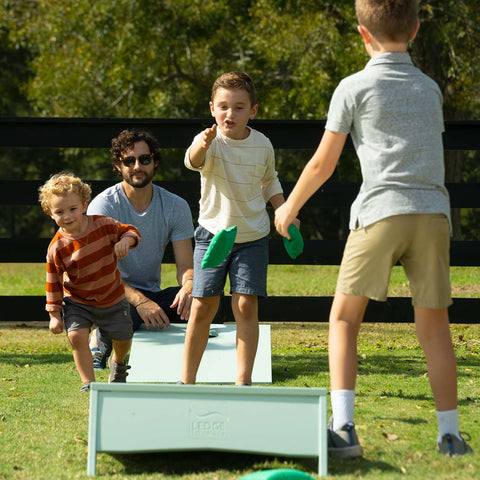 Kids playing outdoor cornhole on the lawn