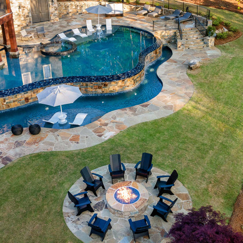Large lawn with adirondack chairs around a fire pit and in-pool furniture inside pool