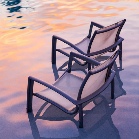 Two metal chairs in pool with sunset lighting