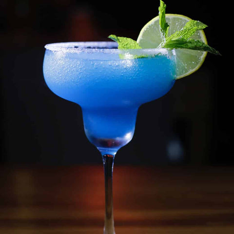 Blue margarita in stemmed glass with lime slice and sugar on rim