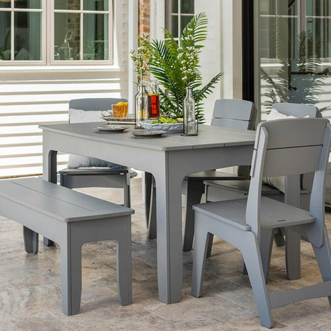 Outdoor dining table with chairs and bench around it, with salad and two plates on table
