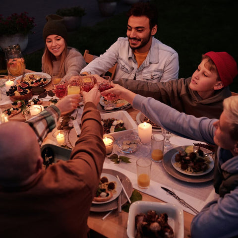 Family clinking glasses over dinner table in a backyard