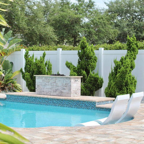 Ledge Lounger products in pool with plants around it