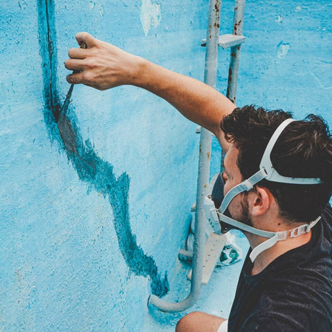 Man repairing cracks in pool walls with putty