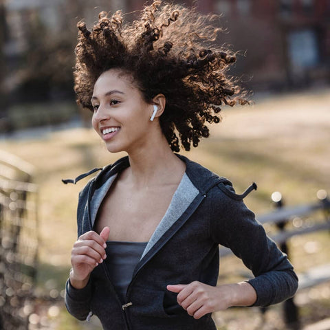 Woman running outside with wireless earbuds in her ears