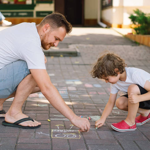 Adult and child drawing with chalk on a patio