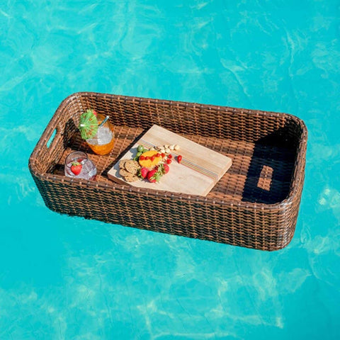 Basket with cutting board and two glasses floating in pool water