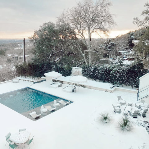 Backyard entirely covered in snow except for rectangular pool