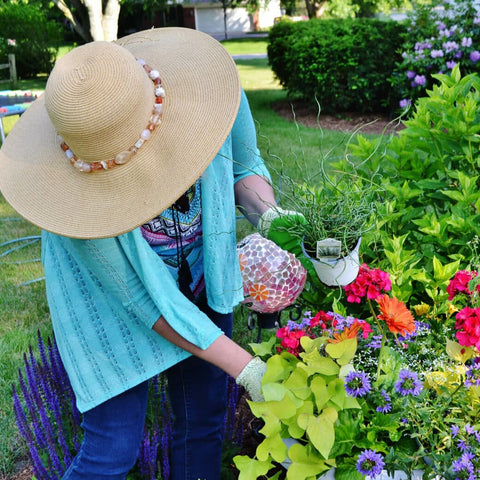 Person with face obscured by large sunhat gardening in backyard