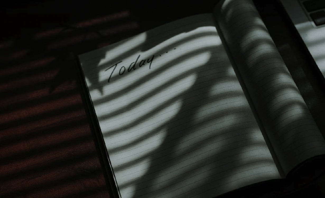 A notebook with 'Today' inscribed on the cover, resting on a shadow-dappled table.