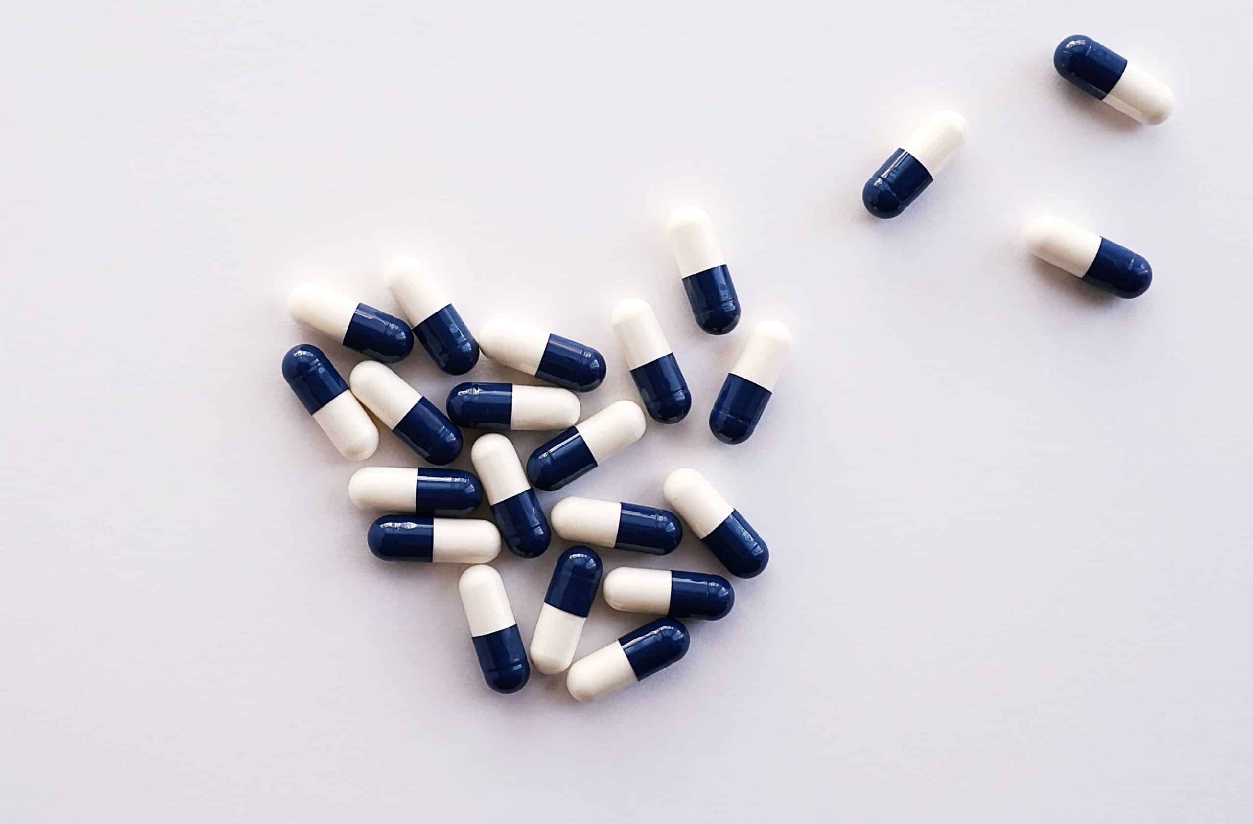 Two tone blue and white colored capsules against a white background