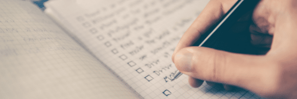 A person writing on a notebook with a pen.