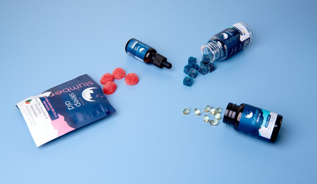 Slumber sleep aid supplements displayed on a blue surface, accompanied by gummies and softgels.