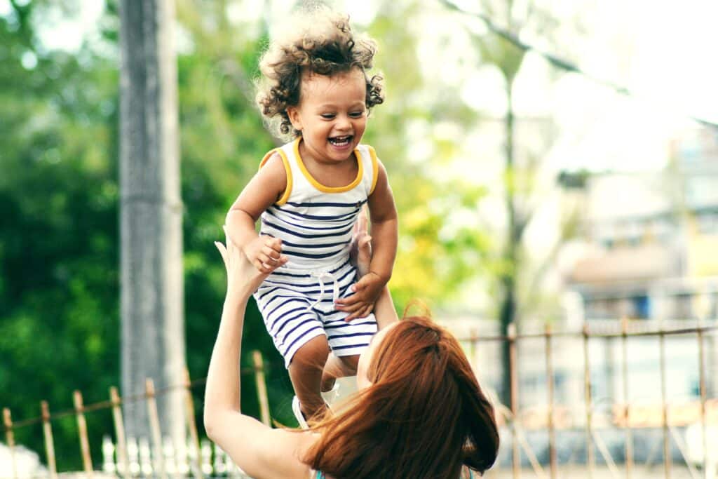A woman is holding a child up in the air.