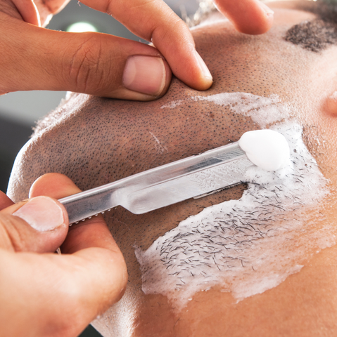 Man getting a straight razor shave at a barbershop.