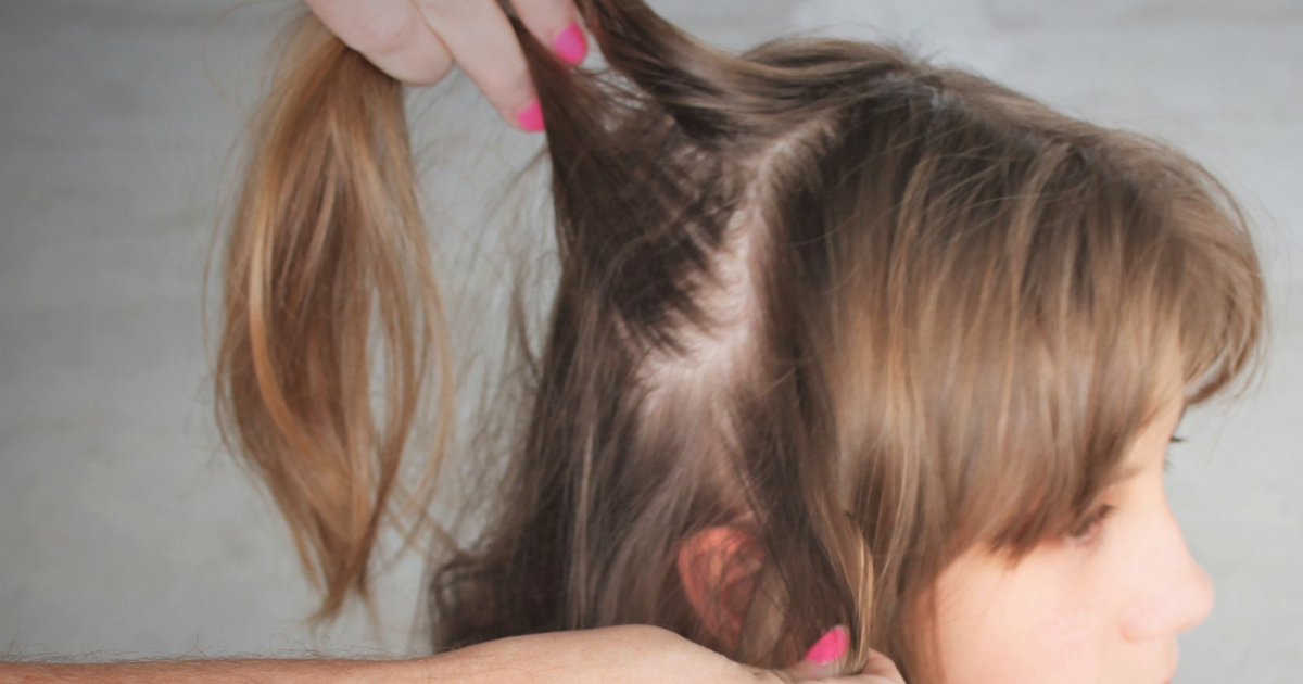 A mom checking her daughter's hair for lice.