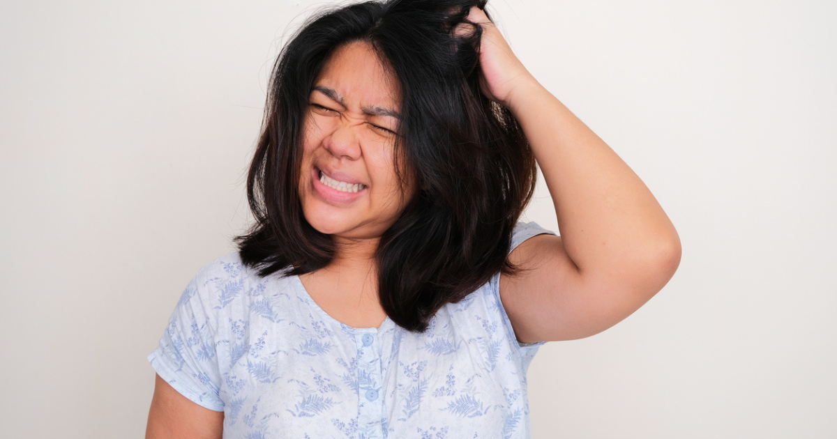 A woman scratching her head because of lice.