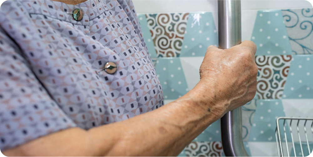 Elderly woman using a bathroom grab bar for safety