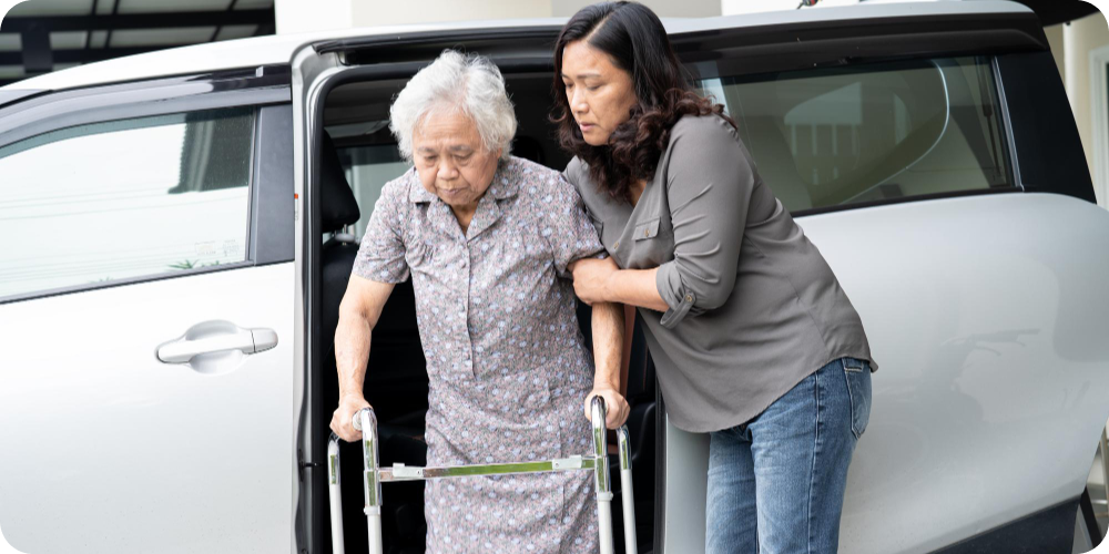 Elderly woman existing van with assistance from family caregiver