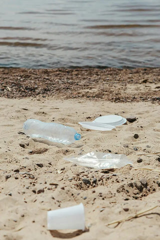 trash, plastic plates and bottles littered on the beach