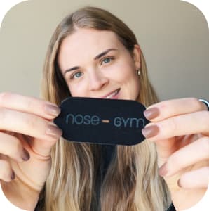 A person holding a 'nose gym' product towards the camera with a smile.