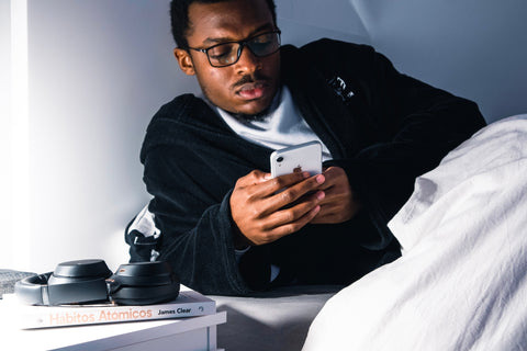 Black male laying in bed with phone in hand