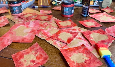 cut up brown paper bags into squares, with red paint added, for background for Valentine's Day cards