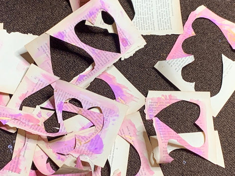 old book pages painted pink and heart shapes cut out of them to make Valentine's Day cards