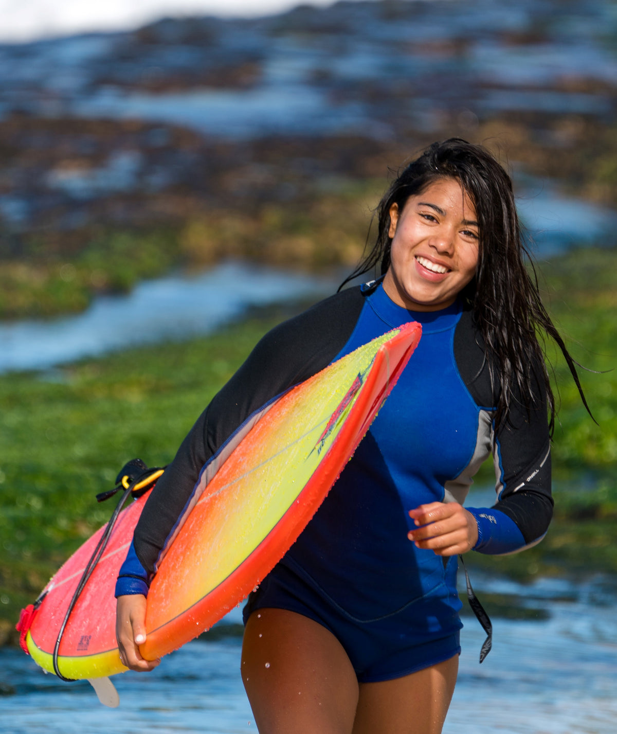 Woman carrying a surfboard | Em & El Organics | Skin Care for the Outdoors