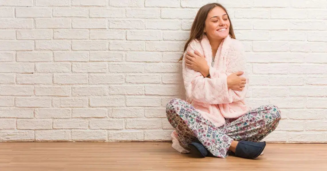 Cozy young woman sitting crossed leg, hugging herself