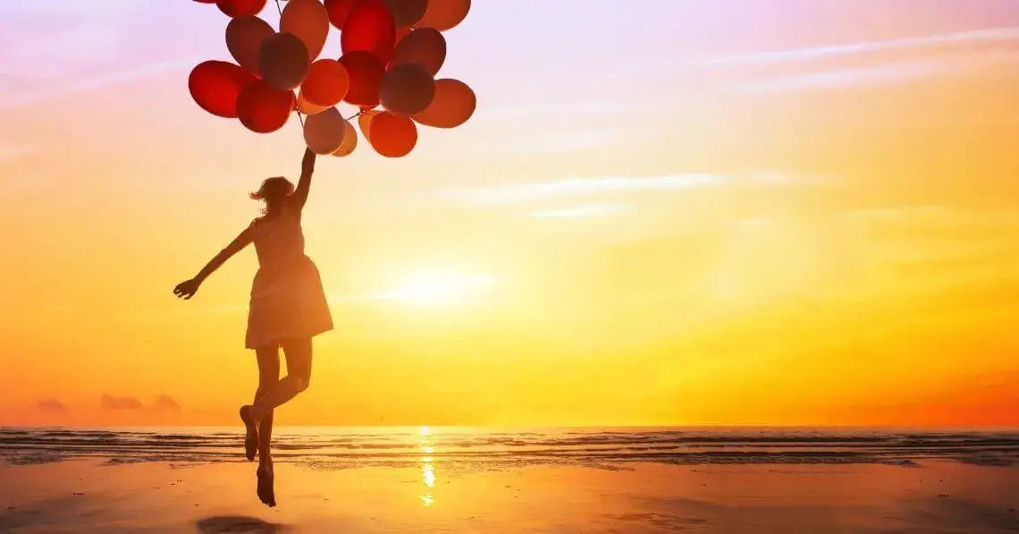 A woman holding onto several red balloons