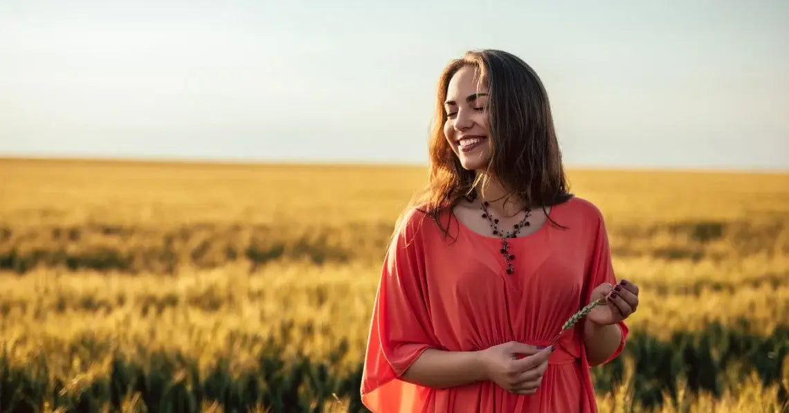 Woman standing in the sunshine in front of a wheat field