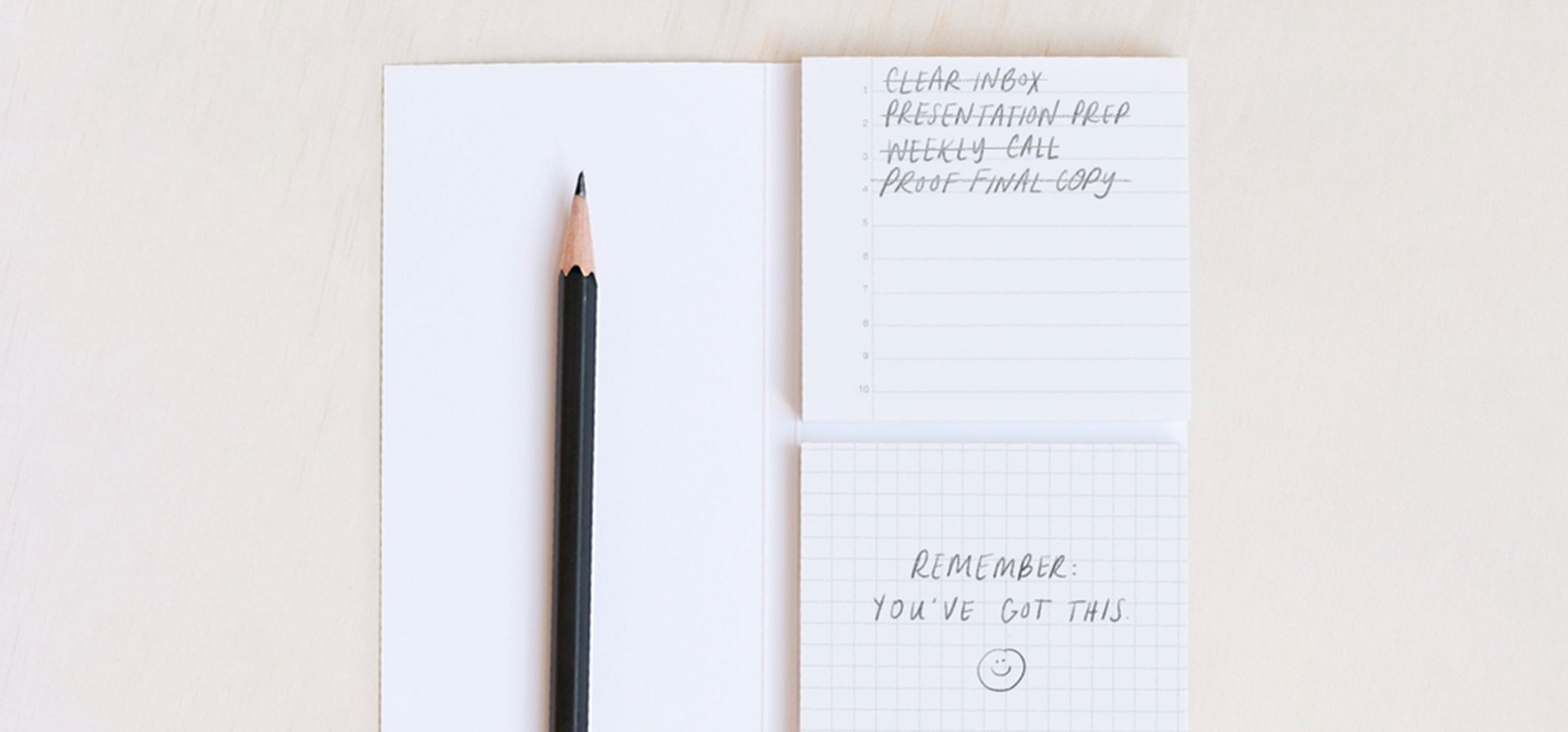 Adhesive pads and a classic no. 2 pencil sit on a cream-colored background. There is a to-do list and encouraging note written on the pages.