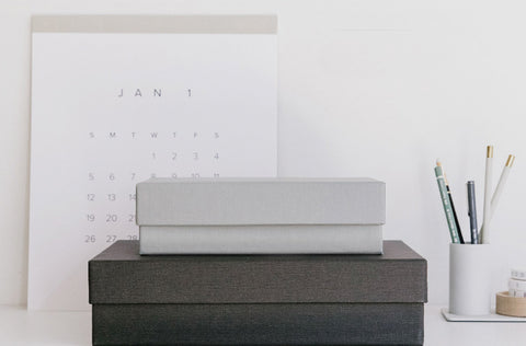 Desktop Storage Boxes sitting on a desk with a calendar and pencils around it