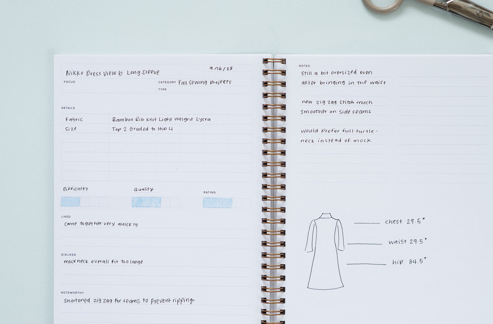 An Activity & Habit Log lies open against a blue background. It is filled in with a hand-written notes tracking a sewing project.