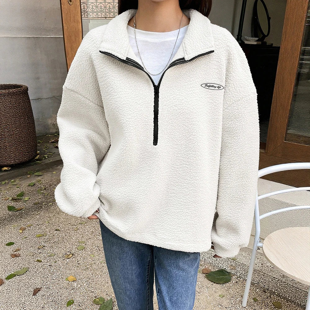 Frau trägt einen Oversized Quarter-Zip-Pullover mit gestickten Details