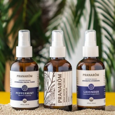 Pranarom Certified Organic Peppermint Hydrosol Facial Toner, Spray Mister, and Lavender Aromatic Hydrosol bottles and green plant.