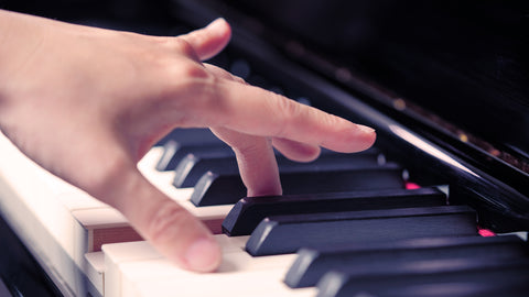 A finger touching a piano key. Others off the keys