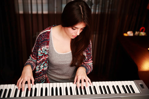 young white woman looking at piano keys and hand carefully