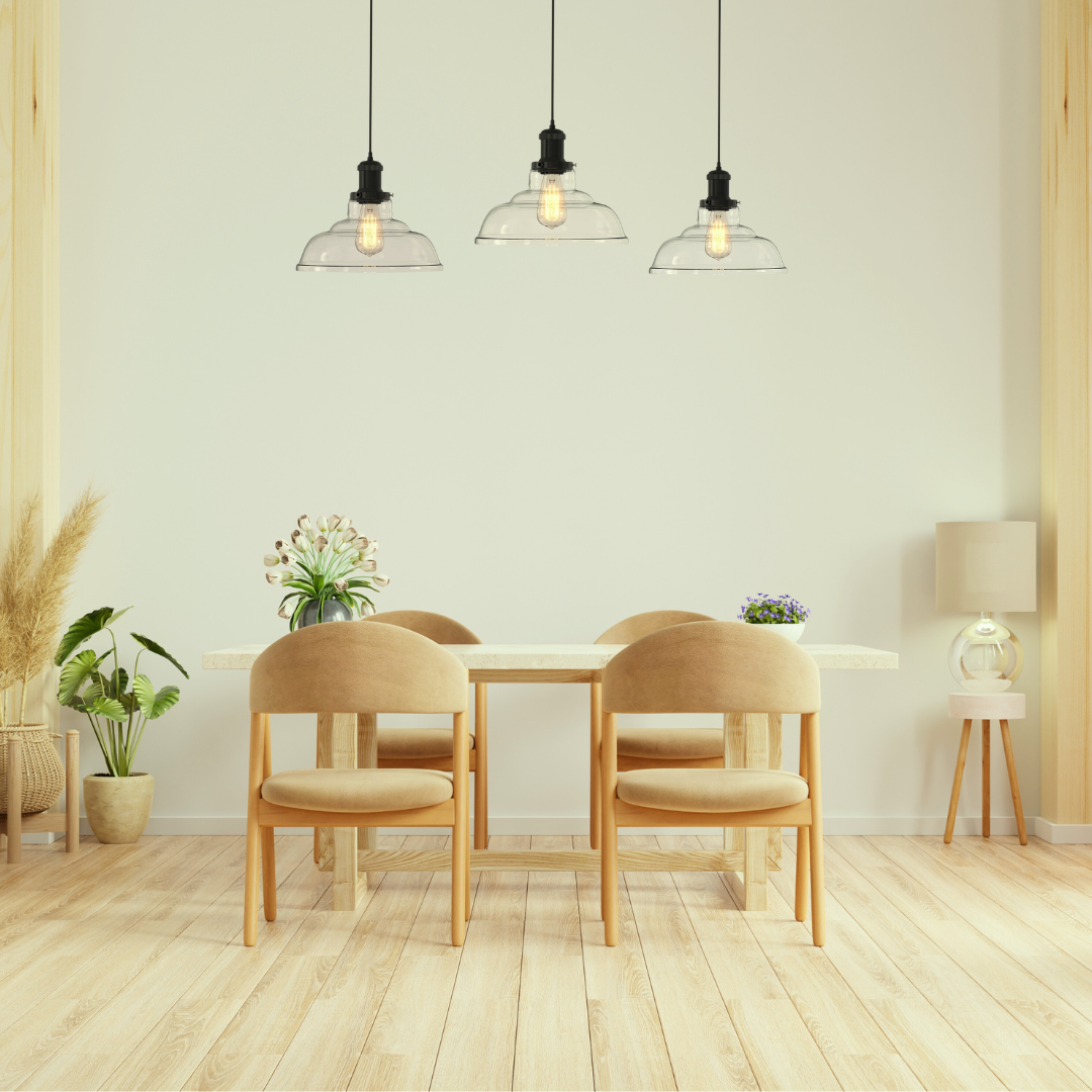 Glass pendant lights elegantly aligned above a dining table in a room with a light beige interior, enhancing the space with their soft glow.