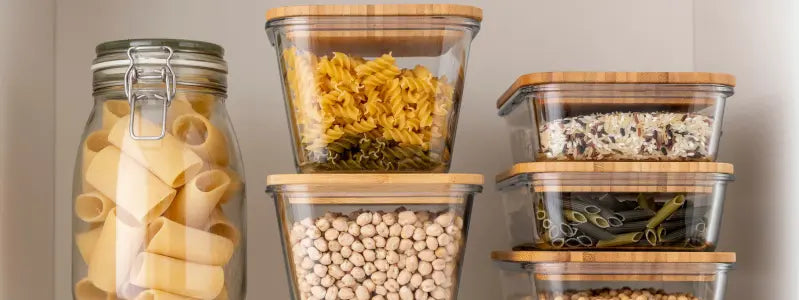 A storage pantry showcasing several glass and wood containers containing dried foods.
