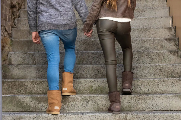 UGG Platinum Short Classic Boot - Australian Made - Female and Male model shot walking up stairs holding hands in Chestnut and Chocolate coloured boots.
