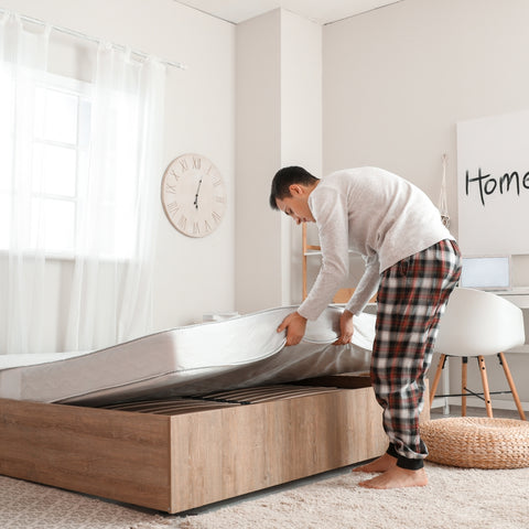 Placing a new mattress on a bed frame.