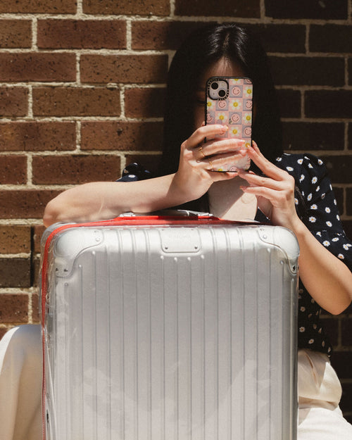 Girl taking a photo on iphone with RIMOWA luggage