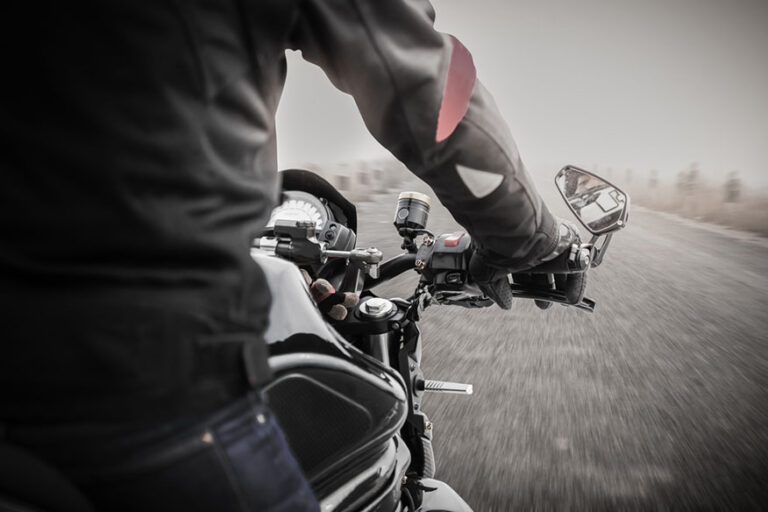 Bikers driving a motorcycle on misty asphalt