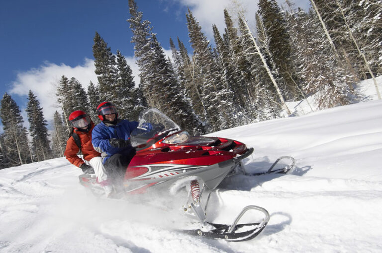 Couple driving snowmobile on snow