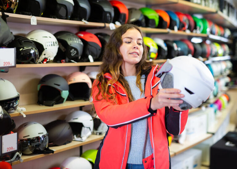 Smiling woman choosing new skiing helmet