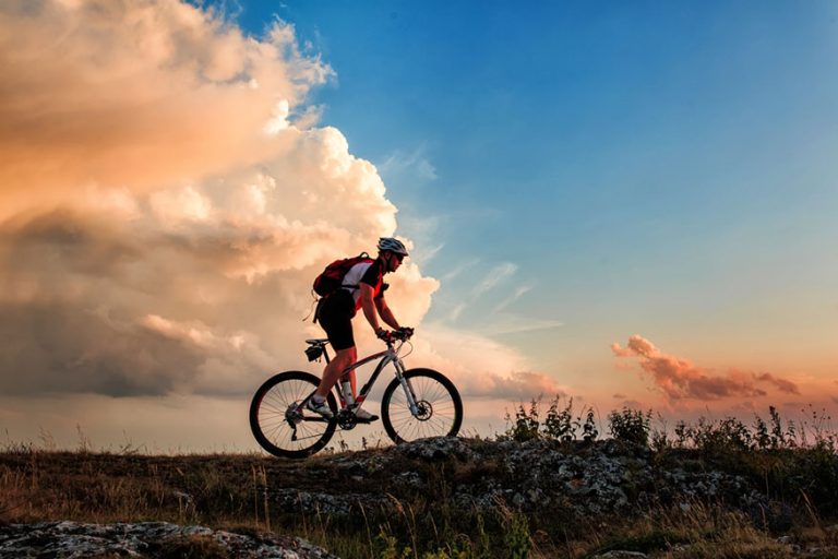 Biker riding on bicycle in mountains at sunset